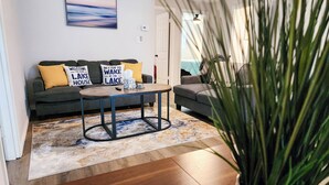A living room with a sofa, coffee table, and a potted plant. - Astor Serene Riverfront Retreat with 2 boat slips and a dock (Astor)