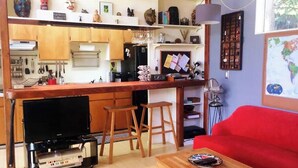 Un espacio habitable compacto con zona de cocina, una mesa de comedor y un sofá rojo.