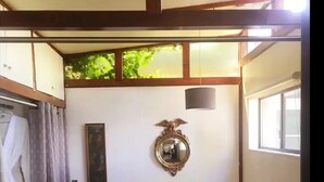 Un dormitorio con cama, mesita de noche, espejo y ventana.