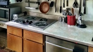 Una cocina con armarios de madera, una estufa a gas, un microondas y varios utensilios colgados en la pared.