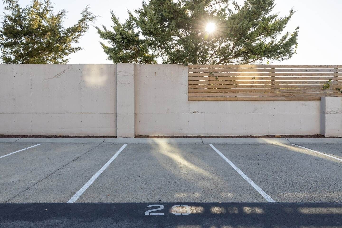Un estacionamiento con espacios delimitados y una pared de hormigón con una sección de listones de madera.