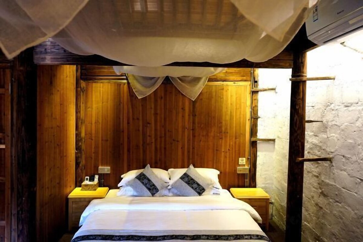A wooden-paneled room with a bed, two bedside tables, and a white wall.
