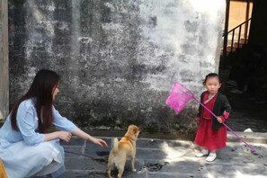 Une personne et un enfant accompagnés d’un chien, dans un cadre extérieur.