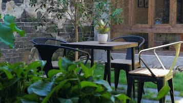 Eine Terrasse mit Tisch und Stühlen, einem Blumentopf und einer Ziegelwand.