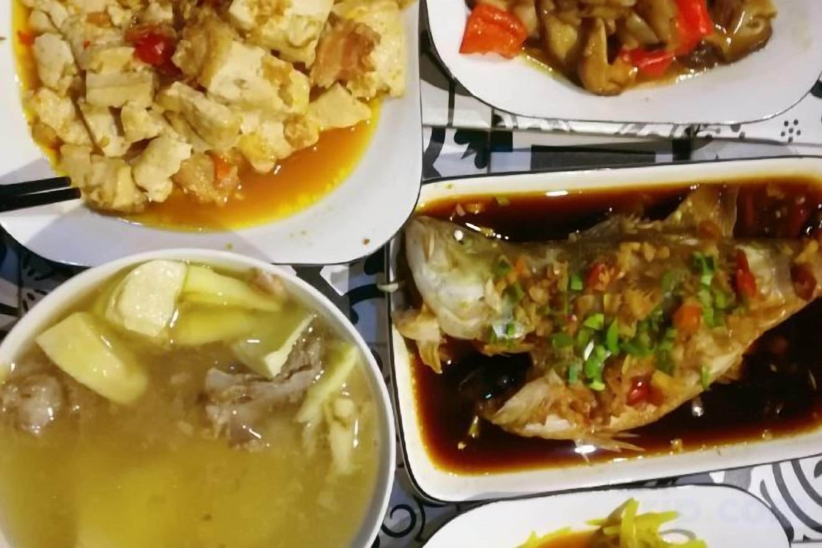 A table with various dishes including a fish, a soup, and a plate with vegetables.