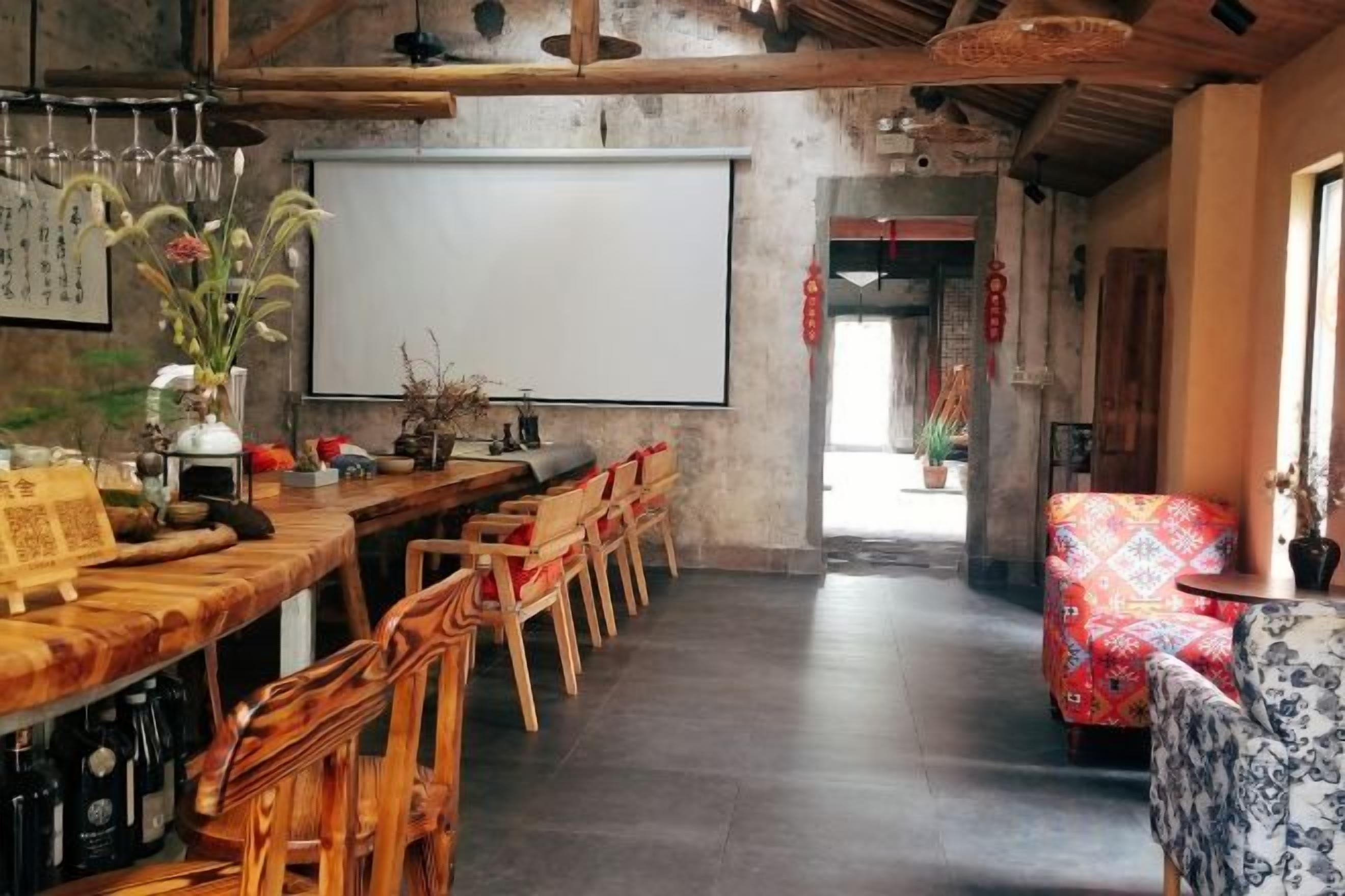 A bar area with wooden furniture, a projector screen, and a seating arrangement.