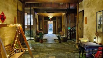 Un intérieur traditionnel avec un sol en pierre, des meubles en bois et un chemin central menant à une sortie.