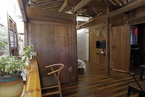 A rustic wooden interior with a wooden bench, a bed, and a TV in a corner. - Yanshe Inn (Huangshan City)