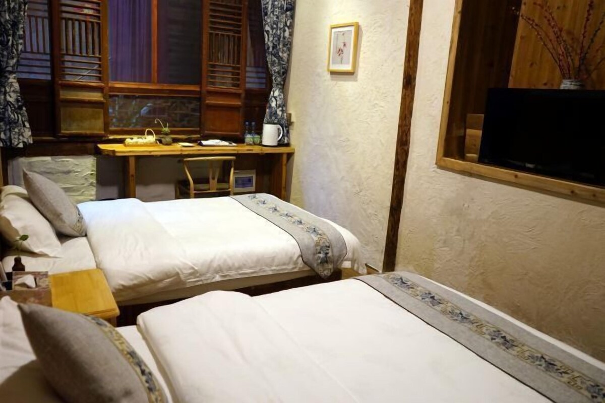 A bedroom with two beds, a desk, and a television.