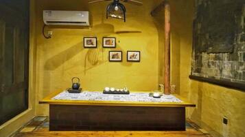A room with a wooden bench, a small table with a kettle, and a ceiling fan.
