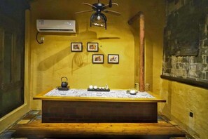 A room with a wooden bench, a small table with a kettle, and a ceiling fan. - Yanshe Inn (Huangshan City)