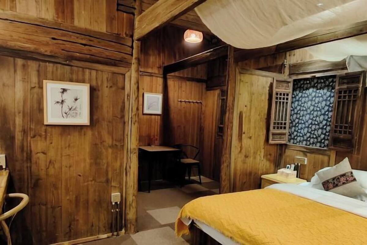 A wooden room with a bed, a desk, and a chair.