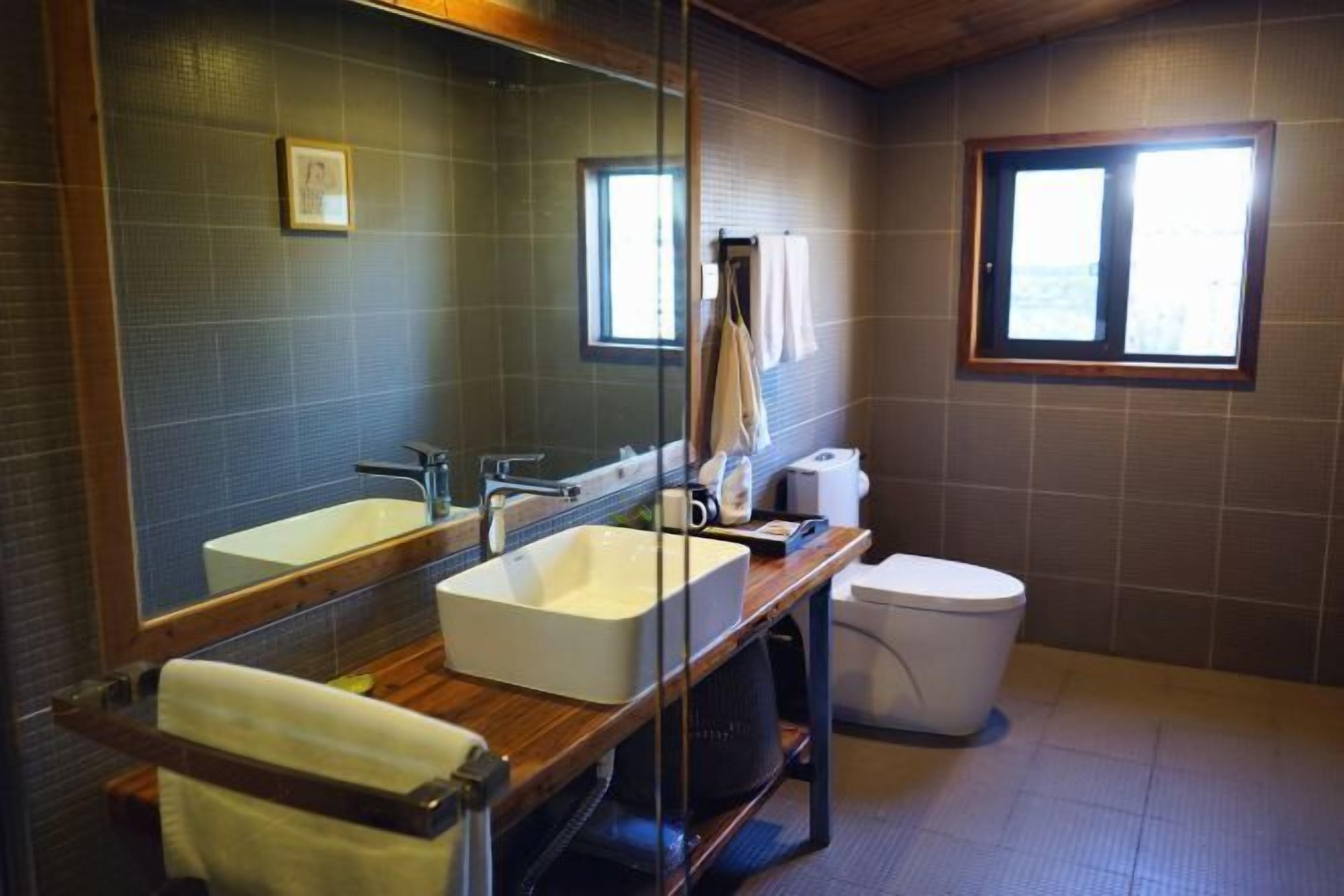 A bathroom with a wooden vanity, two sinks, a toilet, and a large mirror.