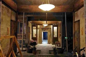 A rustic interior with a wooden ceiling, a central hanging light fixture, and a view into a hallway with a door. - Yanshe Inn (Huangshan City)