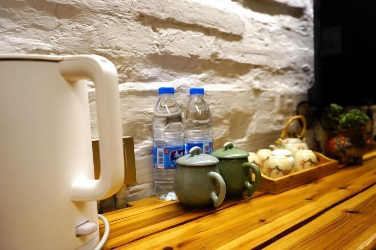 A wooden bench with a white kettle, two water bottles, and a teapot.