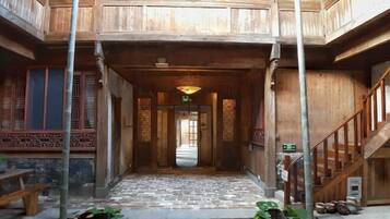 Traditional architecture with a central corridor leading to an open space, flanked by intricately designed wooden structures.