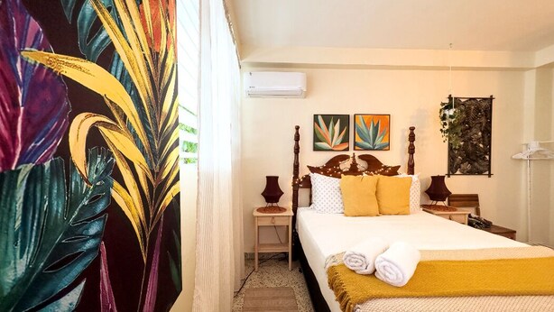 Ein Hotelzimmer mit Bett, Nachttisch, Lampe und einer Wandklimaanlage.