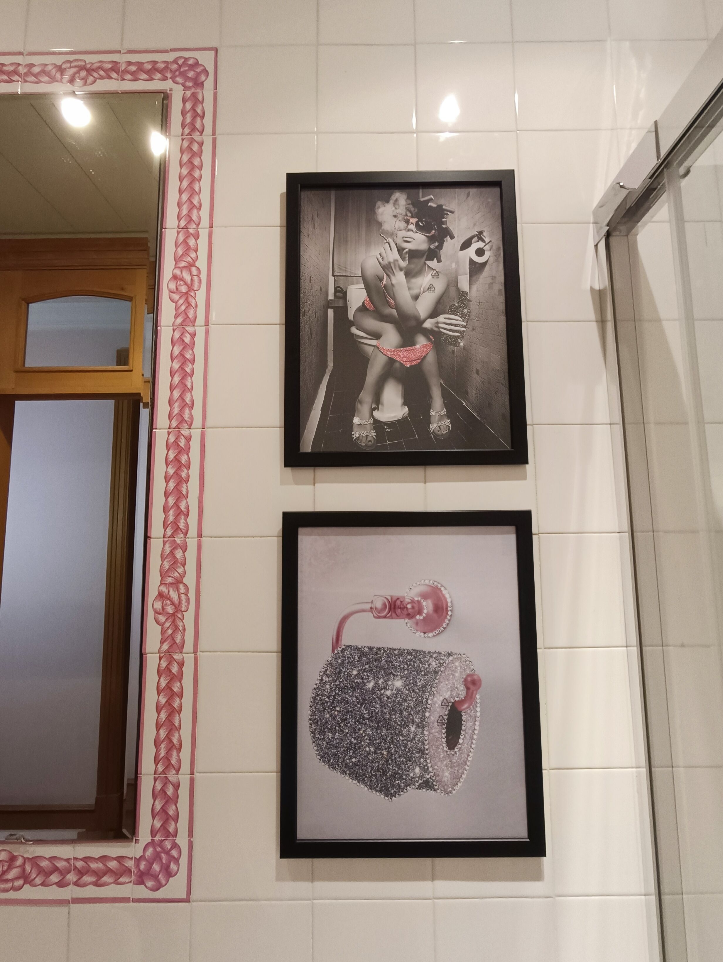 A framed black and white photograph of a person sitting on a toilet, and a framed abstract artwork.