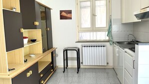 A compact kitchen with a radiator, a window with curtains, a stool, and a sink. - M341 - Marcelli, Three-room apartment with garden close to the sea (Marcelli)
