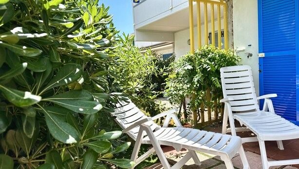 A balcony with two white plastic lounge chairs, a blue door, and a yellow gate. - M341 - Marcelli, Three-room apartment with garden close to the sea (Marcelli)