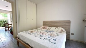 A bedroom with a bed, a wooden headboard, a wardrobe, and a door leading to a balcony. - M341 - Marcelli, Three-room apartment with garden close to the sea (Marcelli)