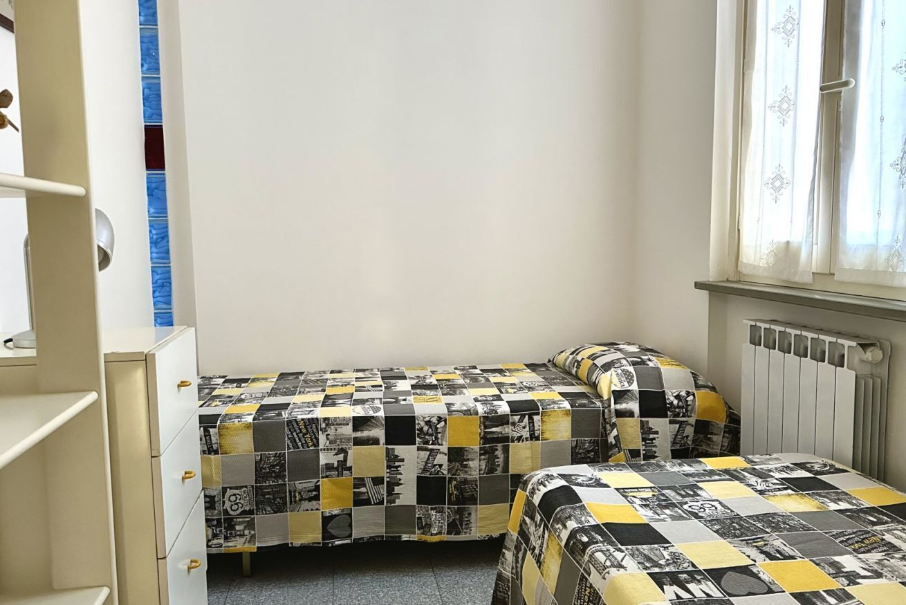 A bedroom with two beds, a wardrobe, and a window with curtains.