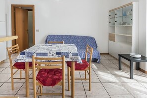 A room with a dining table, chairs, a sofa, a small cabinet, and a tiled floor. - P008 - Porto Recanati, one bedroom apartment with sea view (Porto Recanati)