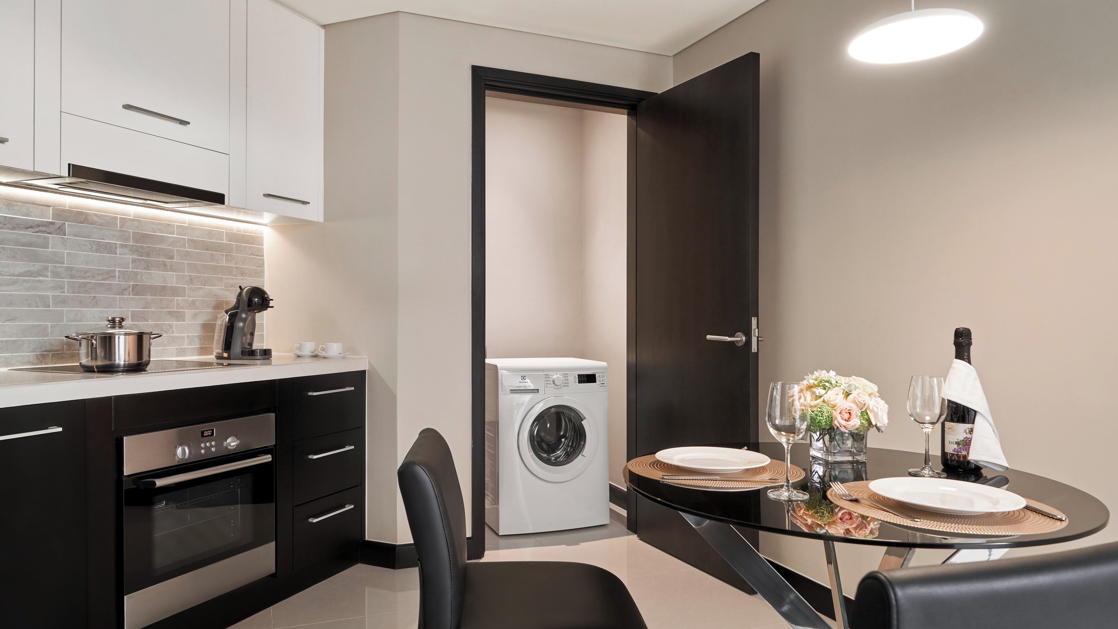 A compact kitchen with a built-in oven, a coffee maker, and a washing machine.
