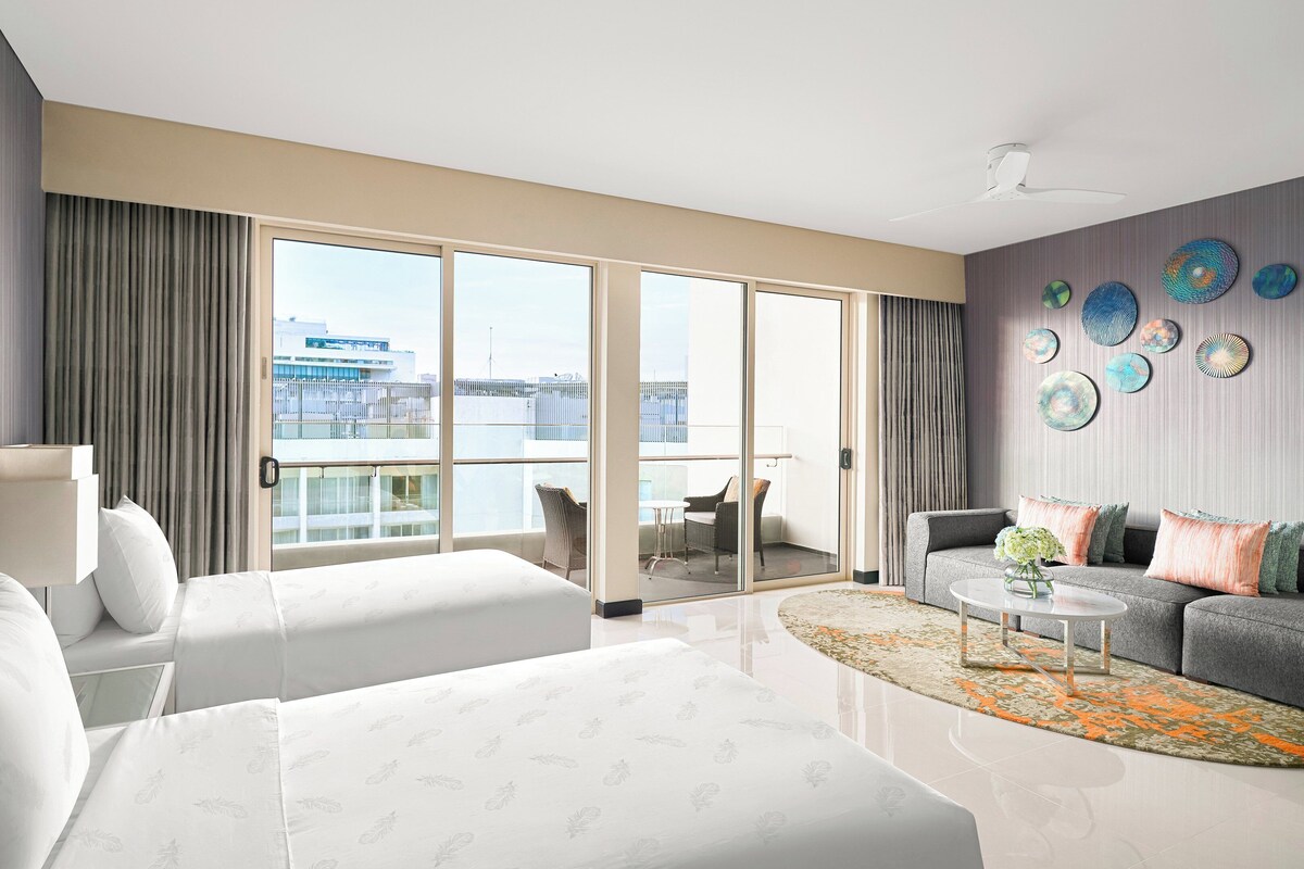 Une chambre d’hôtel avec un grand lit, un canapé, une table basse et un balcon offrant une vue sur la ville.