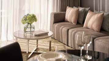 A modern living room with a sofa, a glass coffee table, a vase with flowers, and a book.