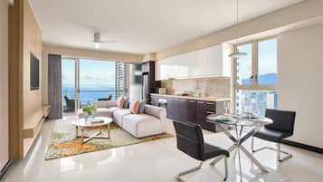 Un appartement moderne comprenant un salon, un coin repas et une cuisine, et doté d’une grande fenêtre offrant une vue sur la ville.