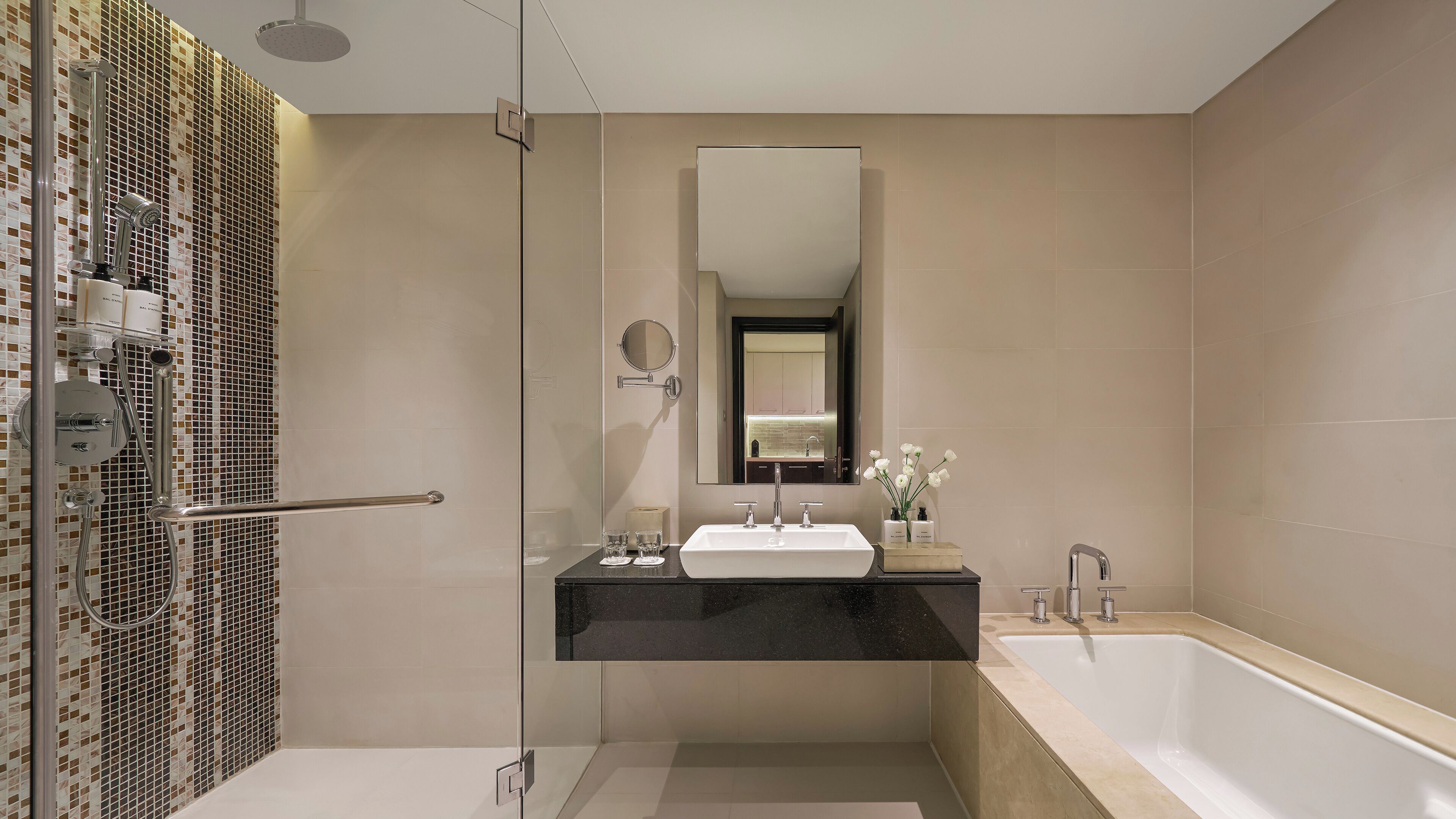 A modern bathroom with a glass shower enclosure, a black countertop sink, a large mirror, and a bathtub.