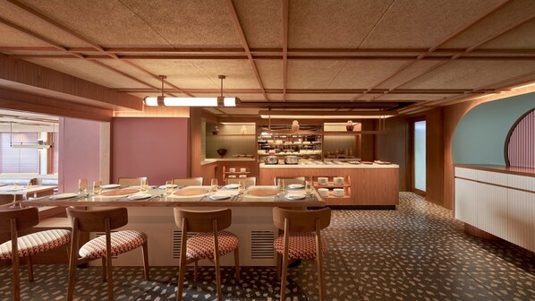Un restaurant doté d’une longue table conviviale, de petits espaces individuels et d’un bar.