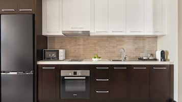 A modern kitchen with a built-in oven, a microwave, a sink, and a coffee machine.