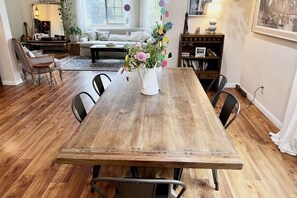 Cozy dining area with a rustic table for four, comfortable seating, and a bookshelf filled with books and decorative items.