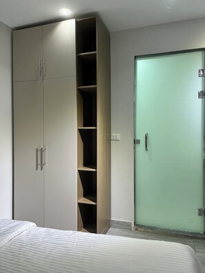 A bedroom with a large wardrobe, a bed with striped bedding, and a green door. - Sphinx apartment hotel  (Giza)