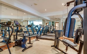 A modern gym with various cardio machines, mirrored walls, and a spacious layout.