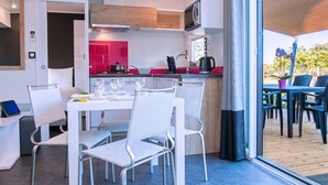 A modern kitchen with white and pink cabinets, a microwave, and a kettle.