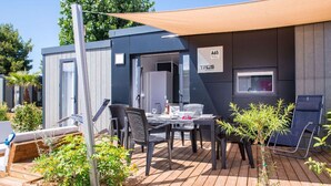 A modern outdoor patio with a table and chairs, a small garden area, and a sign indicating room number A65.