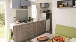 A modern kitchen with a built-in stove, sink, and microwave. There is a green couch in the adjacent living area.