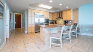 A modern kitchen with a central island, stainless steel appliances, and a breakfast bar. - Stunning Three Bedroom Bayside Condo with Complimentary Boat Slip. (Orange Beach)