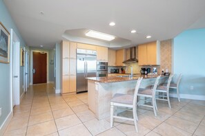 A modern kitchen with a central island, stainless steel appliances, and a breakfast bar. - Stunning Three Bedroom Bayside Condo with Complimentary Boat Slip. (Orange Beach)