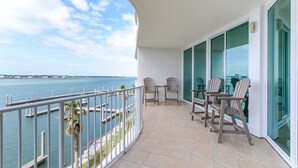 A balcony with a view of the sea, two chairs, and a table. - Stunning Three Bedroom Bayside Condo with Complimentary Boat Slip. (Orange Beach)