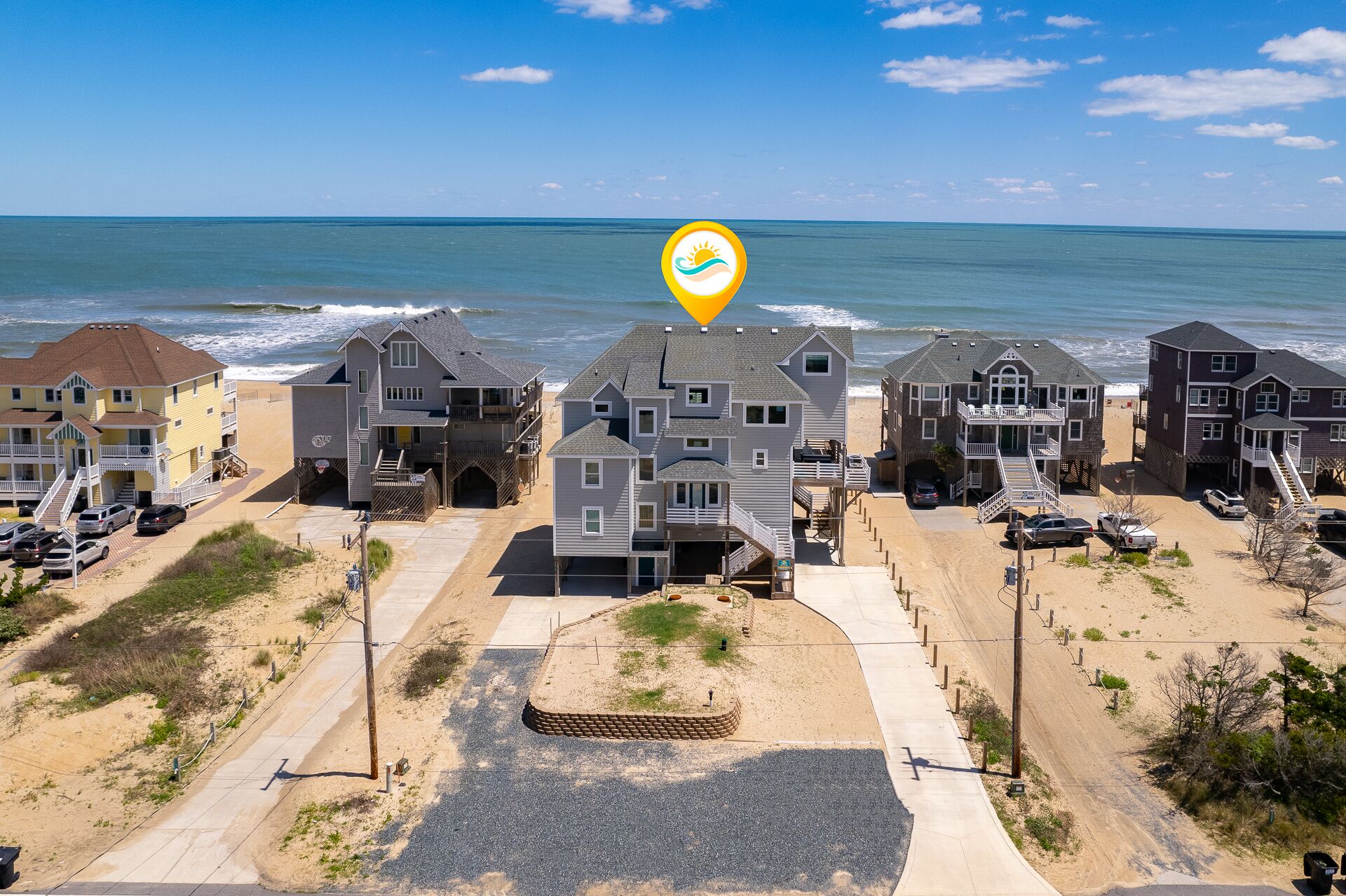 A beachfront residential area with houses, a beach, and a clear view of the ocean.