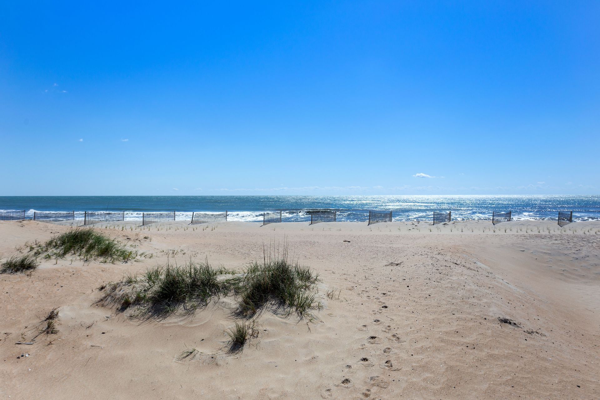 A beach with a fence and sparse vegetation.
