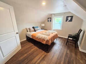 Une chambre à coucher avec un lit, une chaise, une fenêtre et une porte.