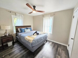 A bedroom with a bed, a ceiling fan, a nightstand, a lamp, and a window with curtains. - 4 bd Pet-Friendly Home- Steps to Millcreek Park (Youngstown)
