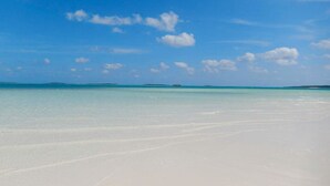 Een strand met helder turquoise water en een breed zandstrand.