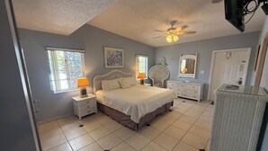 A bedroom with a bed, nightstands, a dresser, a ceiling fan, and a television. - Capt. Joe's Key Colony Beach 5-Star Pool & Beach access (Key Colony Beach)