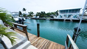 A wooden dock leading to a marina with boats and a building with a blue roof. - Capt. Joe's Key Colony Beach 5-Star Pool & Beach access (Key Colony Beach)